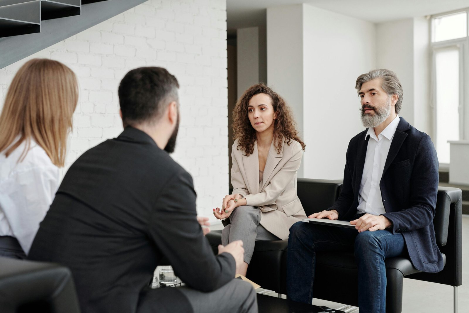 Four professionals engaged in a serious business discussion indoors.